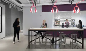 Inside Spotify Studios NYC, people gather around a communal table, with iconic headphone lights overhead.