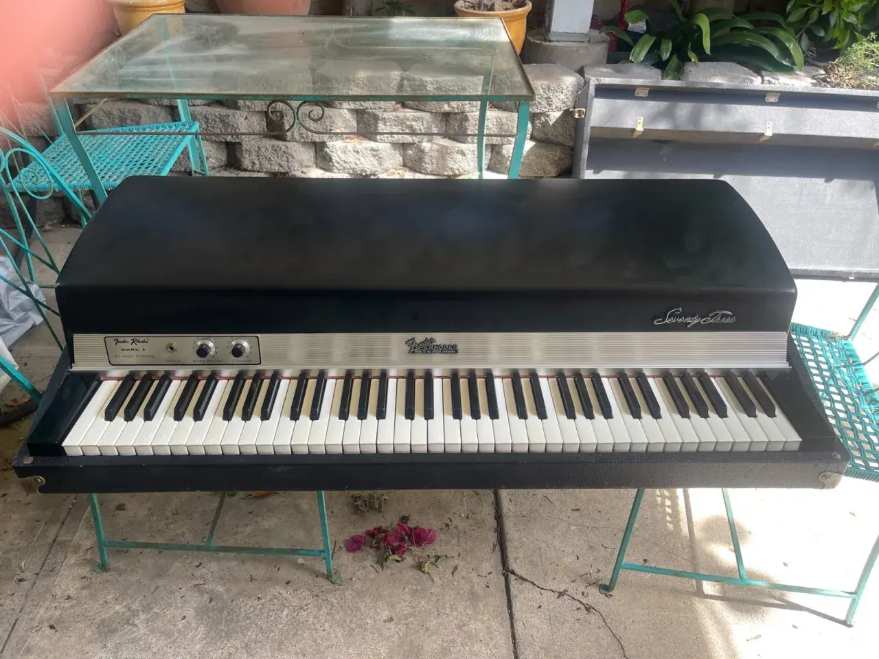 A vintage Fender Rhodes Stage Piano Mark I, a classic among labs vintage keys, sits on a teal metal stand outdoors.
