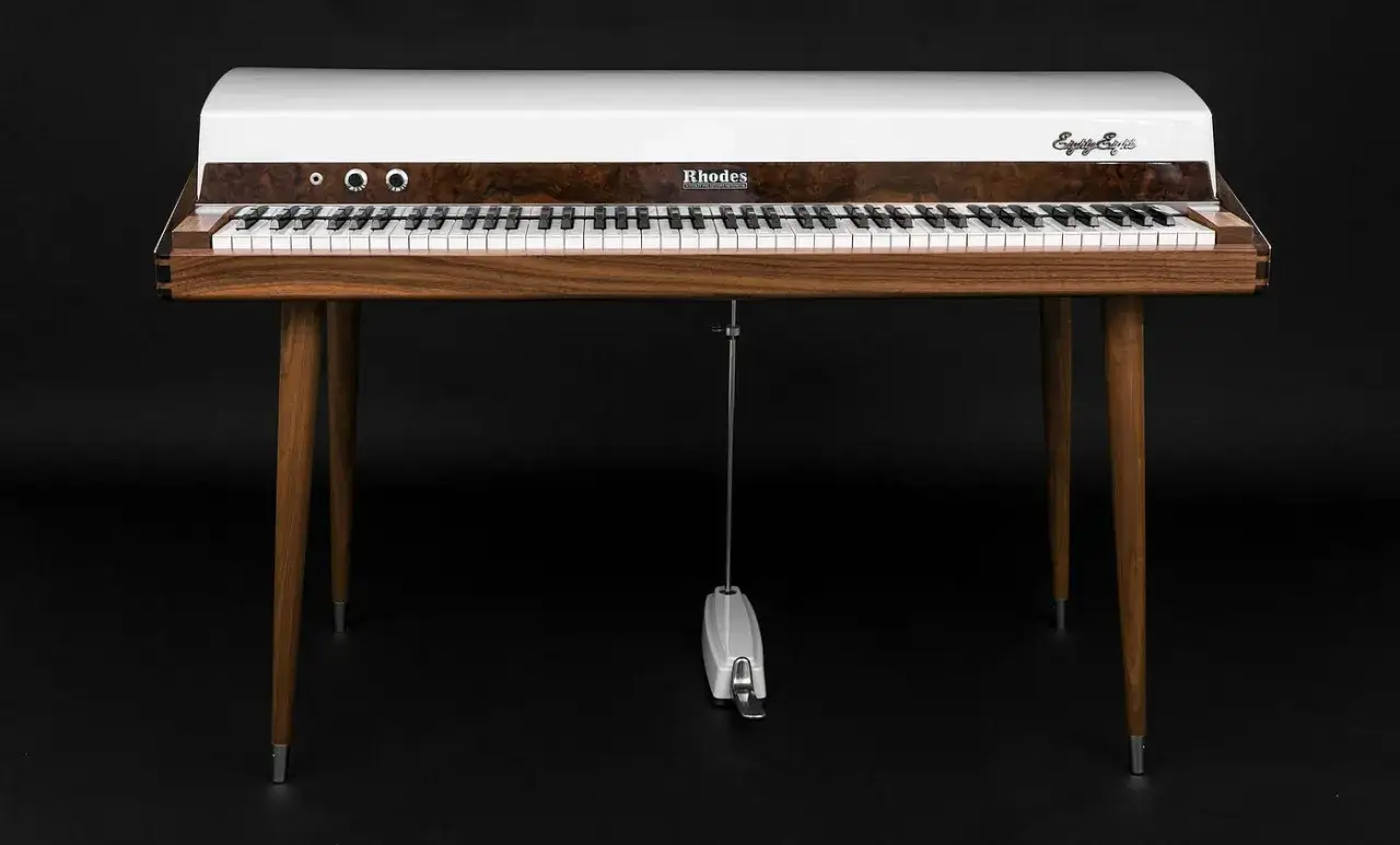 A vintage Rhodes electric piano with a white top, wood grain panel, and tapered legs. This iconic instrument, with its classic keys, evokes the sound of labs and timeless music.