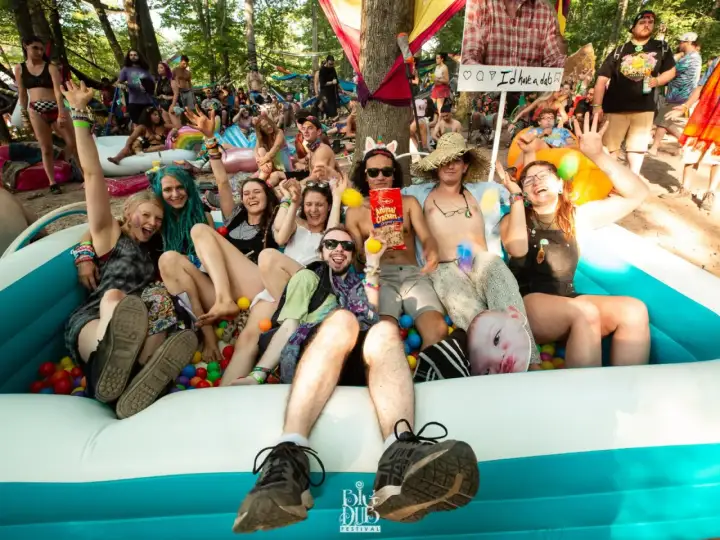 A group of friends enjoys a ball pit at the lil dub festival, laughing and posing for a photo.